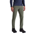 Une personne porte le pantalon La Sportiva Trail Guard Pants Men's en vert olive, avec une chemise à manches longues marine et des chaussures de randonnée noires, sur un fond blanc uni - idéal pour les amateurs de randonnée.