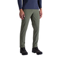 Une personne portant un pantalon La Sportiva West Crest Pants Men's vert olive, une chemise à manches longues marine et des chaussures de randonnée noires se tient debout sur un fond blanc uni.