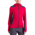 Une femme porte le La Sportiva Aequilibrium Thermal Hoody en rose vif avec des accents gris foncé et un tissu Polartec Power Grid, avec une fermeture à glissière sur le devant et des trous pour les pouces aux poignets, associé à un short gris. L'arrière-plan est blanc.
