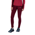 A person wearing a long-sleeved red top, La Sportiva Primal Thermo Tight Women’s maroon leggings featuring a small logo on the thigh, and black and blue trail running shoes stands ready for a winter adventure against a white background.