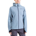 A woman wearing the La Sportiva Descender Storm Jacket—light blue softshell with cozy fleece interior, front zipper, thumbholes, and La Sportiva logo on chest and sleeve—pairs it with dark gray pants against a white background.