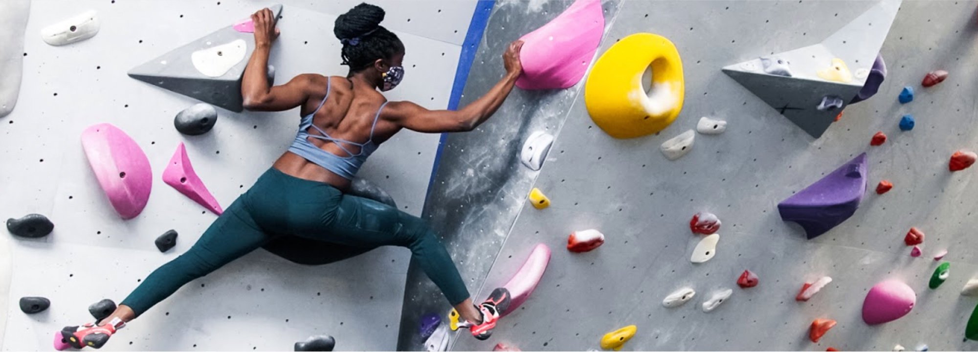 Person climbing on a colorful rock wall with various holds.