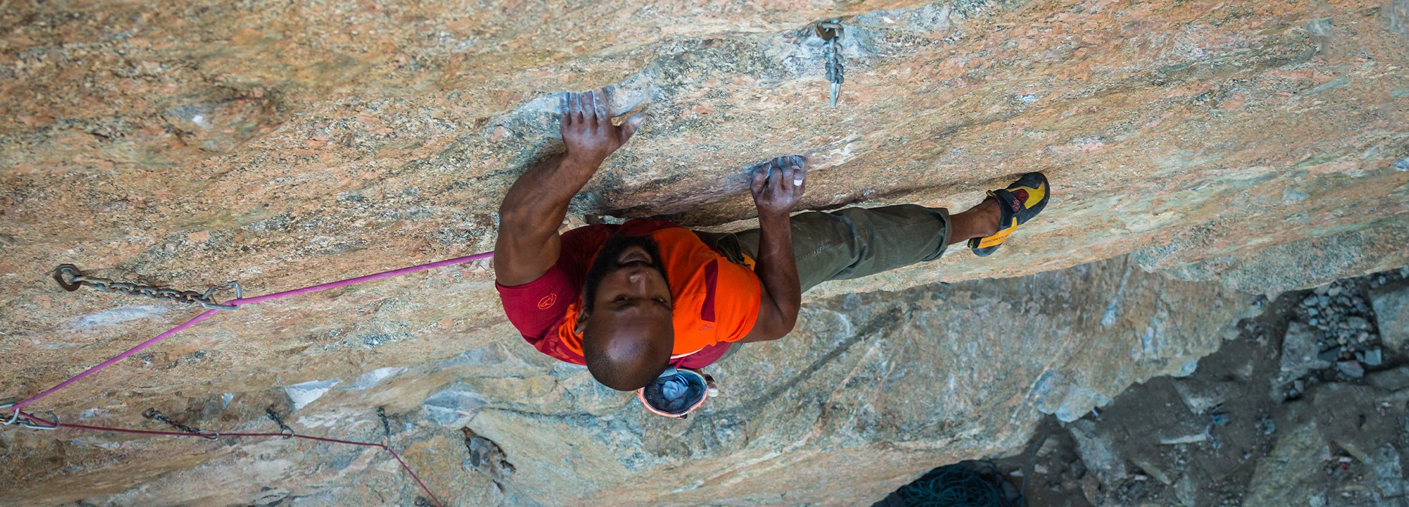 Person rock climbing on a rocky wall with ropes and equipment.