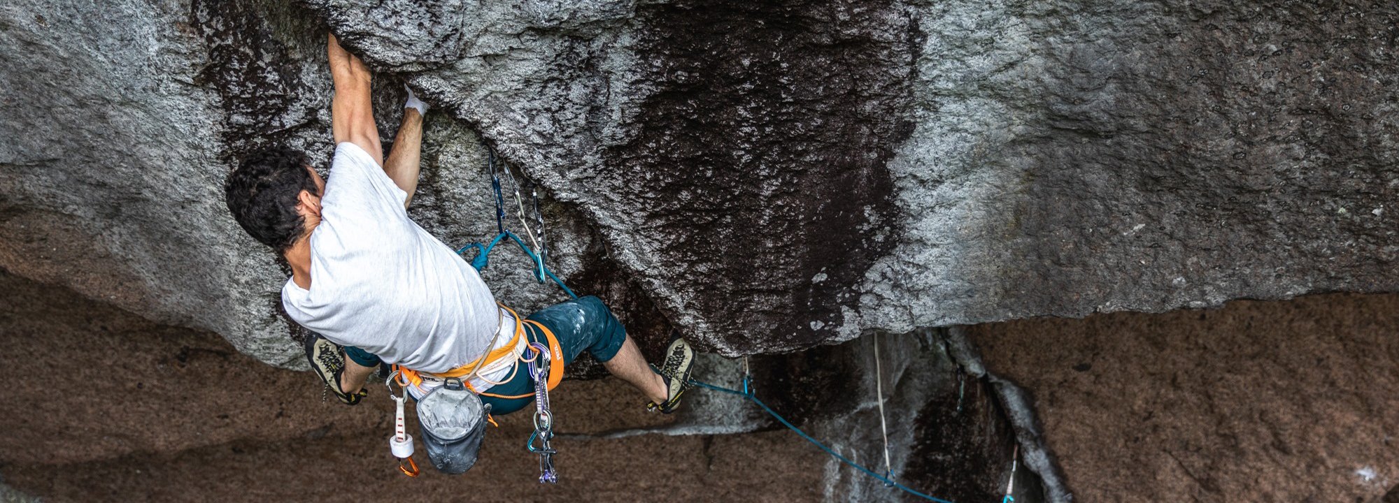 Person rock climbing on a large overhanging rock formation.