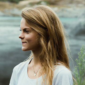 Woman with long blonde hair standing by a body of water