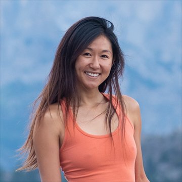 Woman in an orange tank top standing against a blue mountainous background